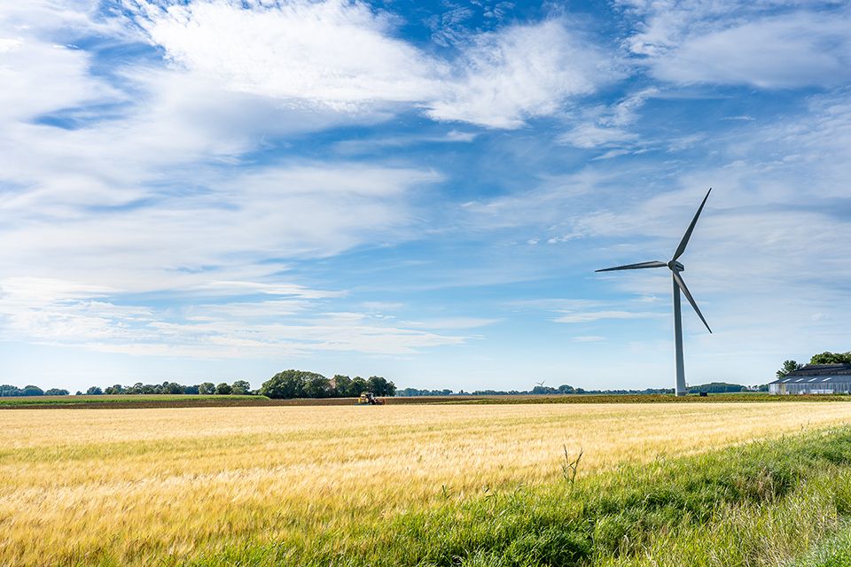 Majestic landscape view of land with a windmill for generating electricity under a cloudy sky